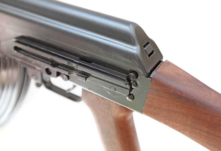 The Zastava ZPAP M70 rifle features a lock that secures the recoil spring guide. A button on the left rear of the receiver must be pressed to allow the recoil spring guide to be pushed in to release the dust cover. The lock will also hold the recoil spring guide in so that the dust cover can be re-installed.