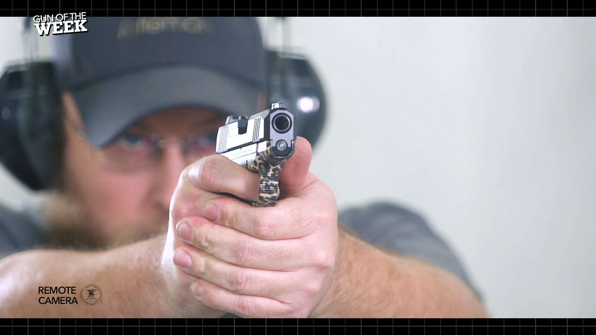 Man wearing cap earmuffs shooting RUGER MAX-9 pistol handgun downrange forward view remote camera