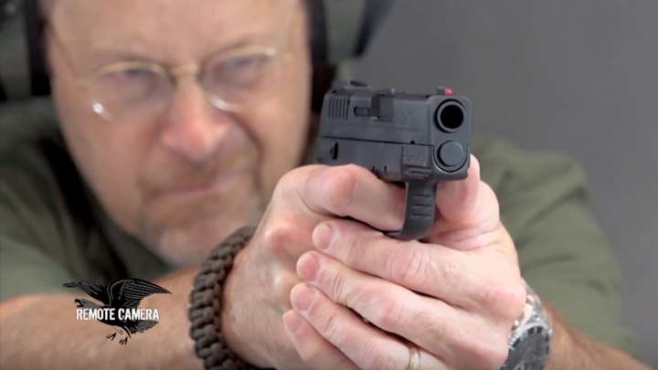 Man with protective shooting gear on range shooting a Springfield XDe pistol.