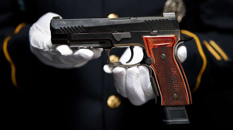 Man wearing white gloves presents the SIG Sauer P320-M17 Ceremonial pistol.