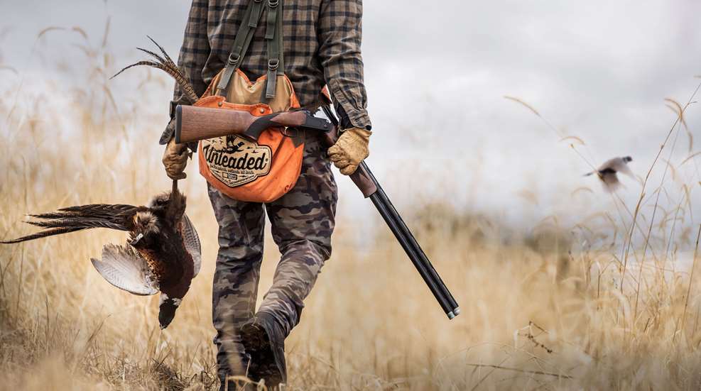 Mossberg over-under shotgun in hand man hunter outdoors pheasant grass bird hunting