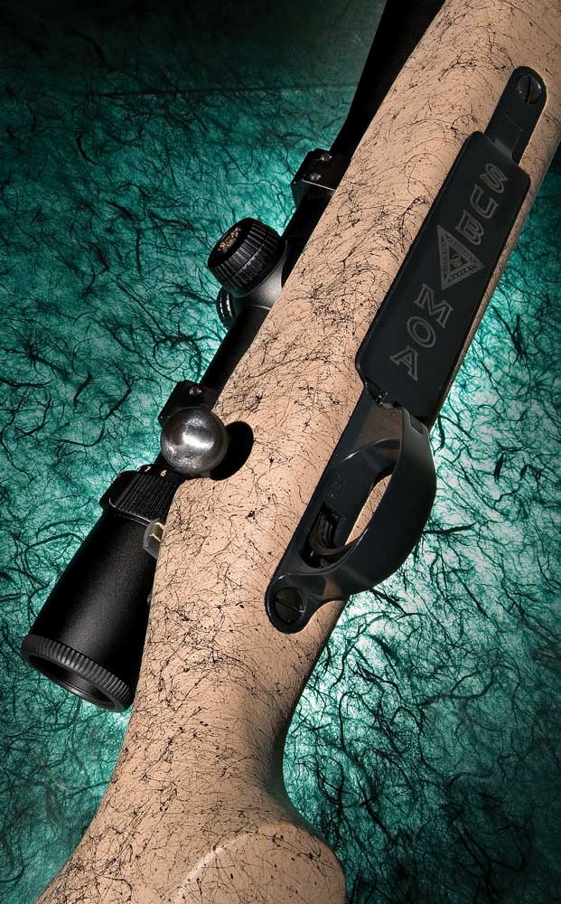Weatherby Vanguard bolt-action rifle brown tan gunstock black action barrel riflescope dark background underside gun bottom action trigger