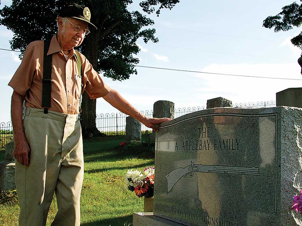 man outdoors cemetary headstone