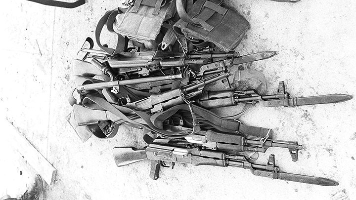 Multiple styles of AK-47 rifles captured on Grenada. An extra barrel for a Czech vz. 52/57 LMG is seen on top of the pile.