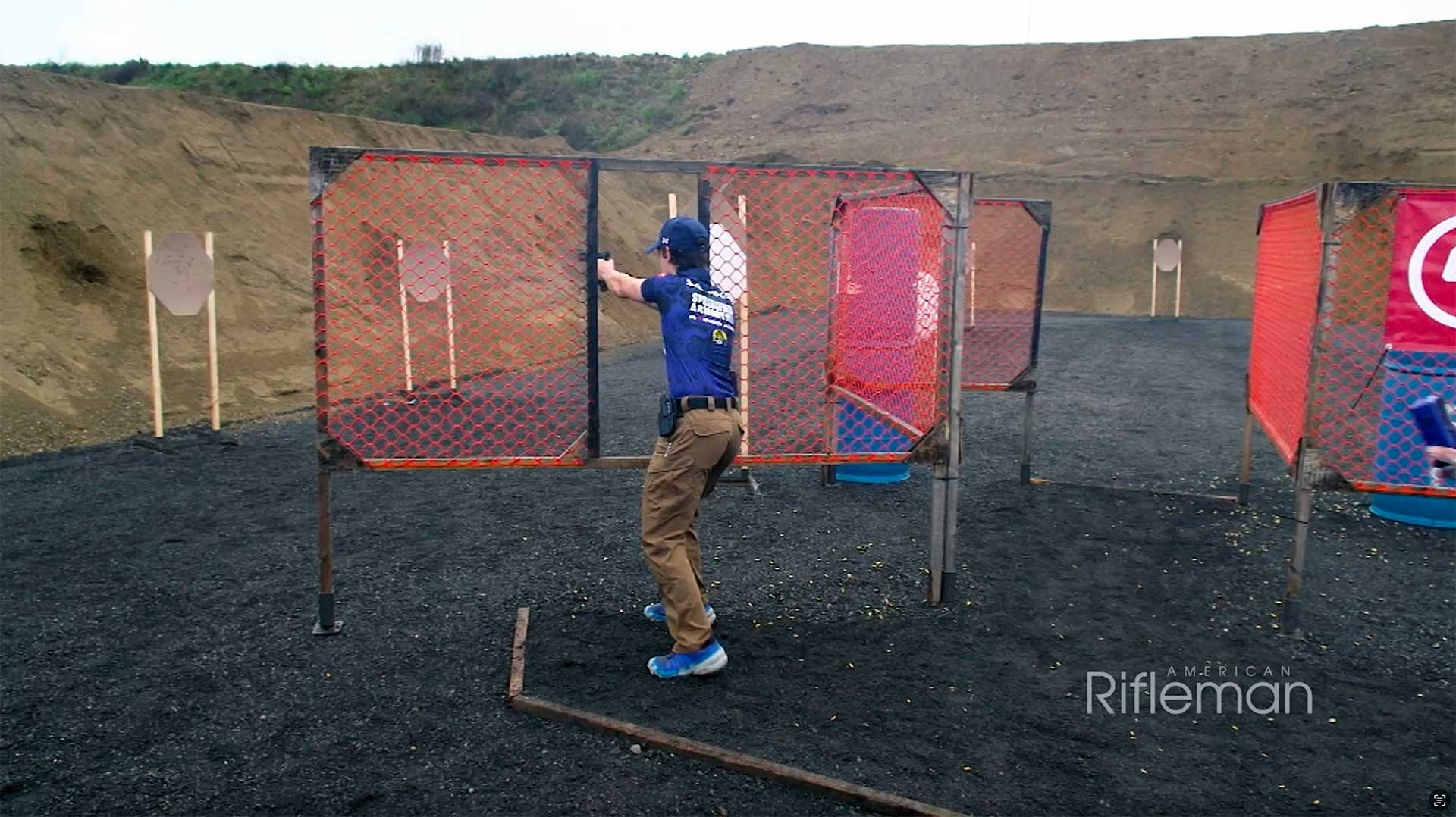 Man shooting cardboard targets with a pistol on an outdoor range.