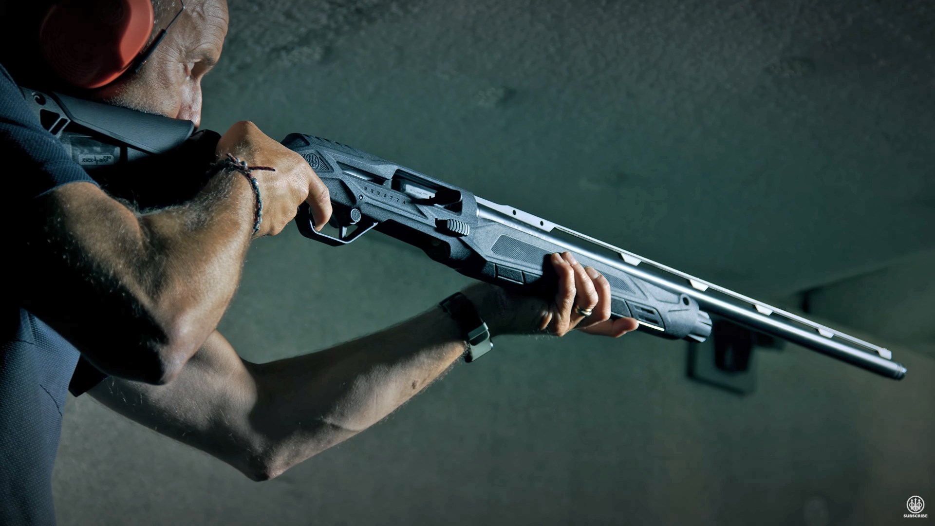 Man aiming an all-black Beretta AX800 Suprema shotgun on an indoor range.