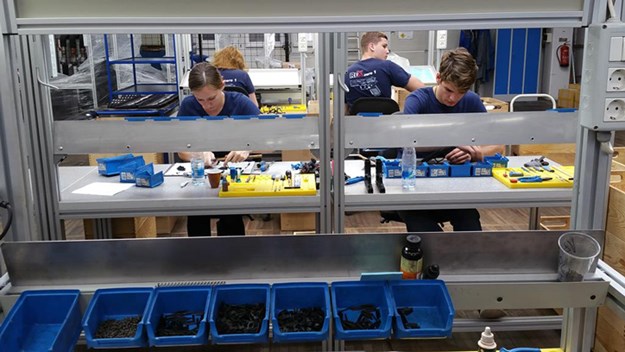 workers manufacturing gun parts pieces organized