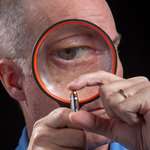 man inspecting a cartridge with a magnifying glass