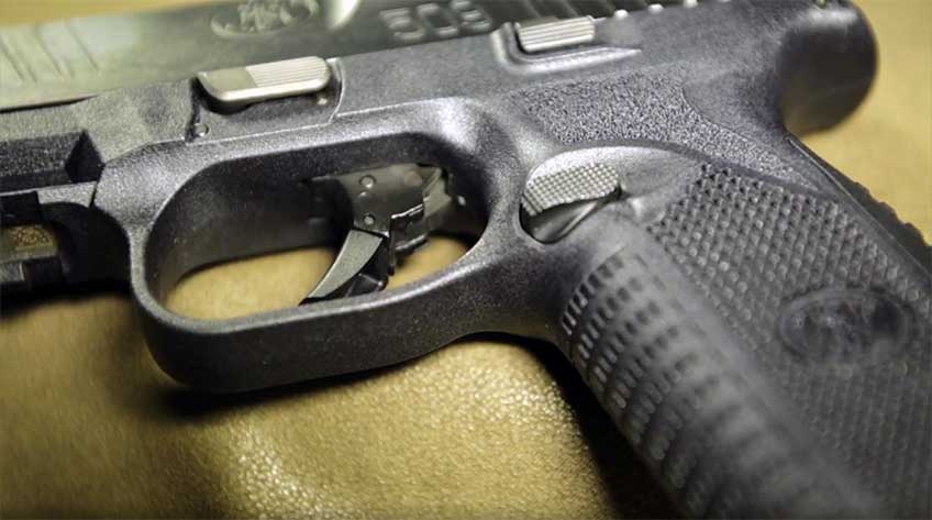 Left side of the FN 509, showing closeup of the strong-side controls of the gun, including magazine release, slide stop, trigger and takedown lever.