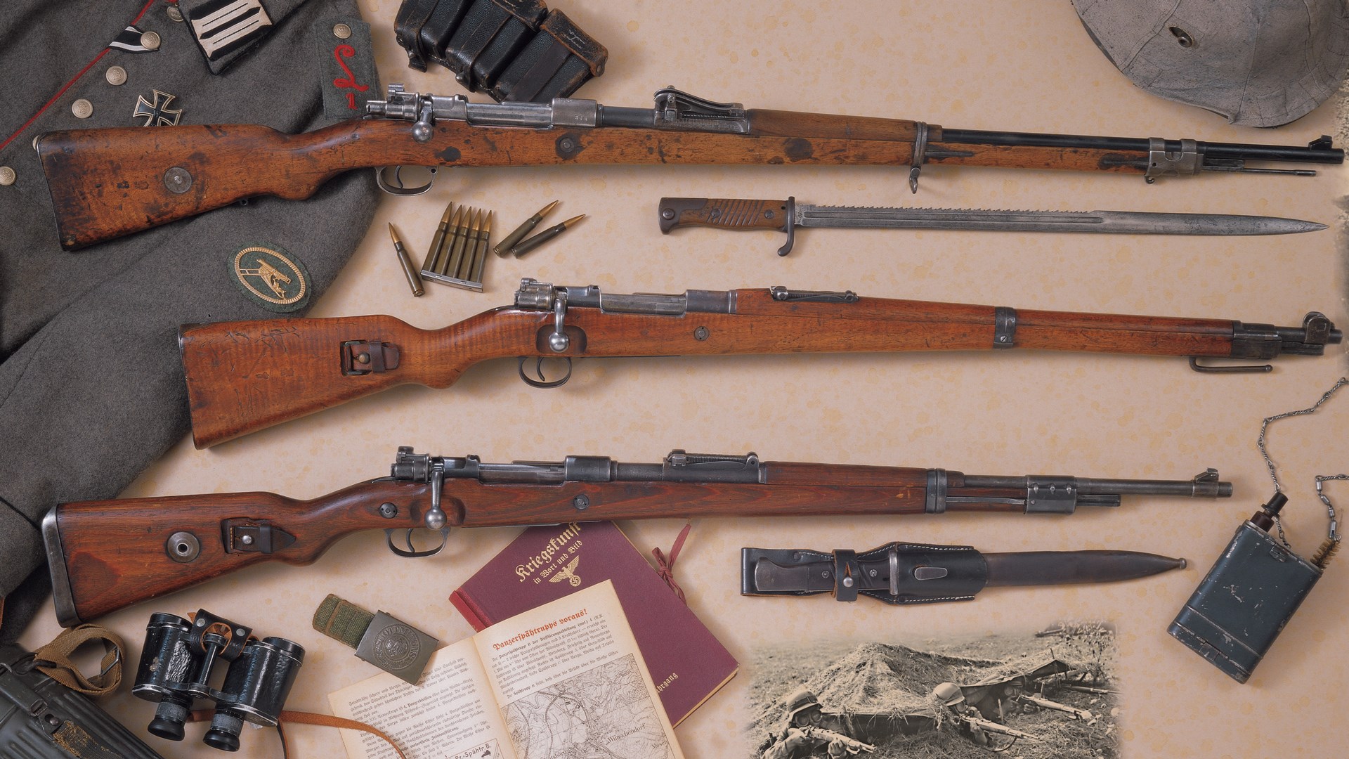 Three mauser bolt-action carbines arranged stack with ammunition uniform binoculars hat bayonet blade book