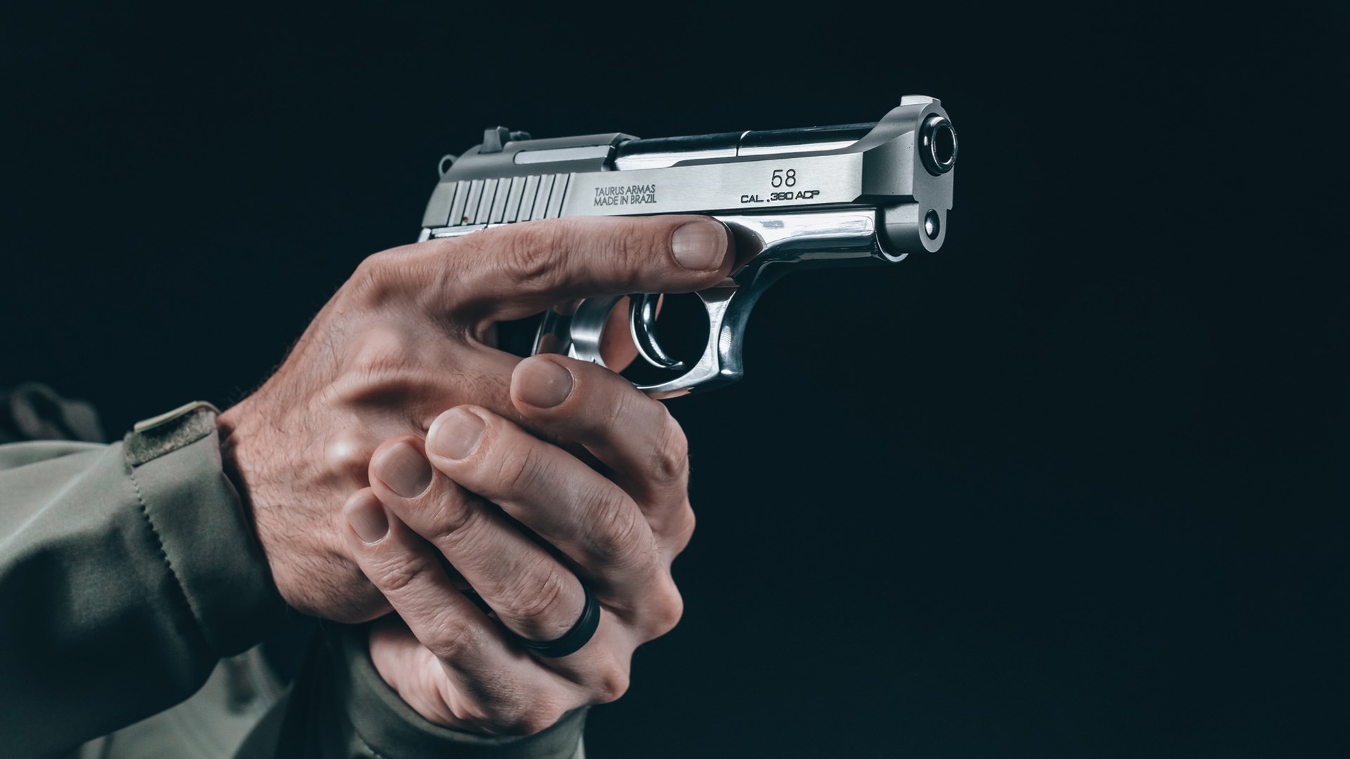 Man aiming a stainless-steel Taurus 58 handgun.