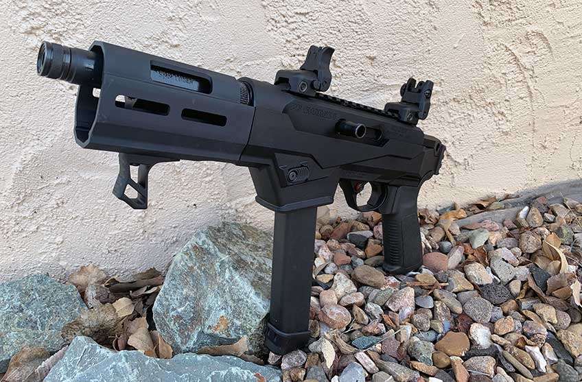 Black and gray colored pistol standing on pebbles with concrete background