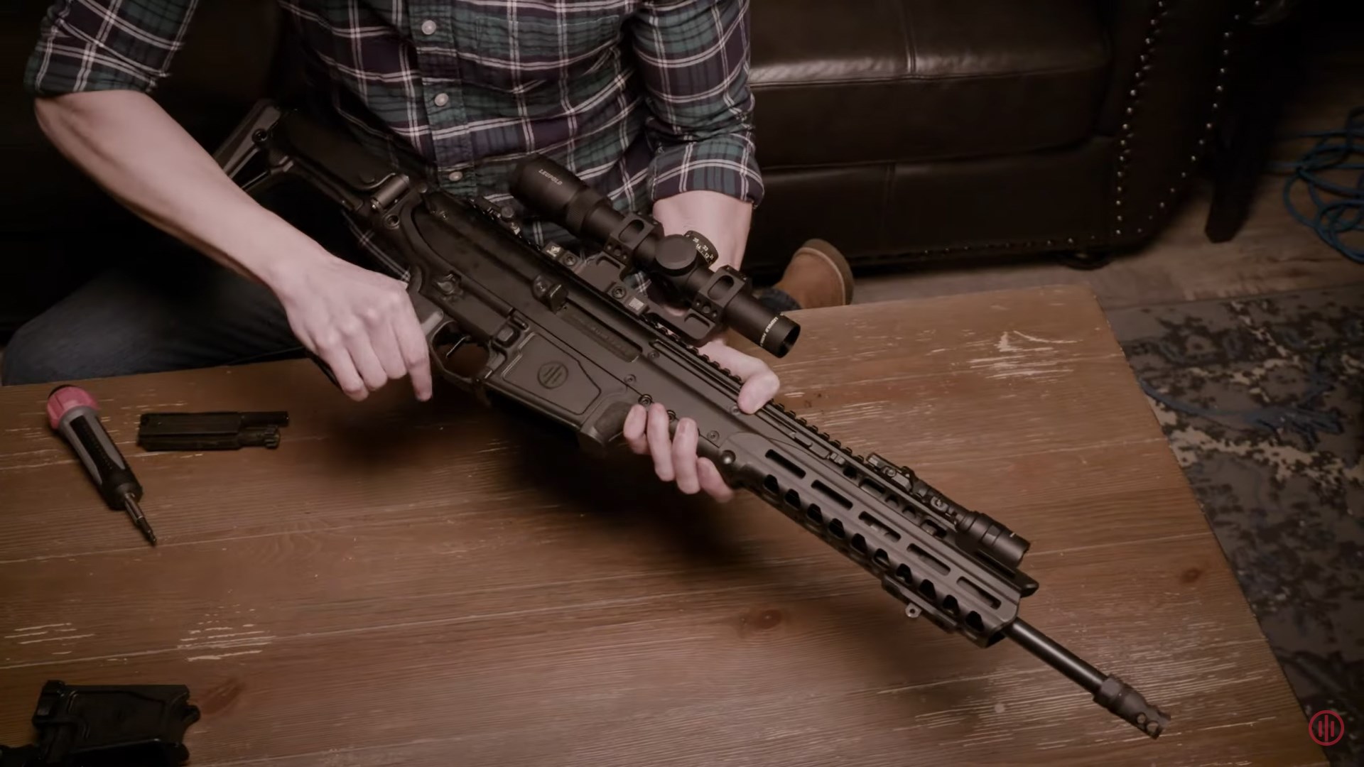 PWS UXR right-side view man installing lower receiver wood table tools indoors couch carpet