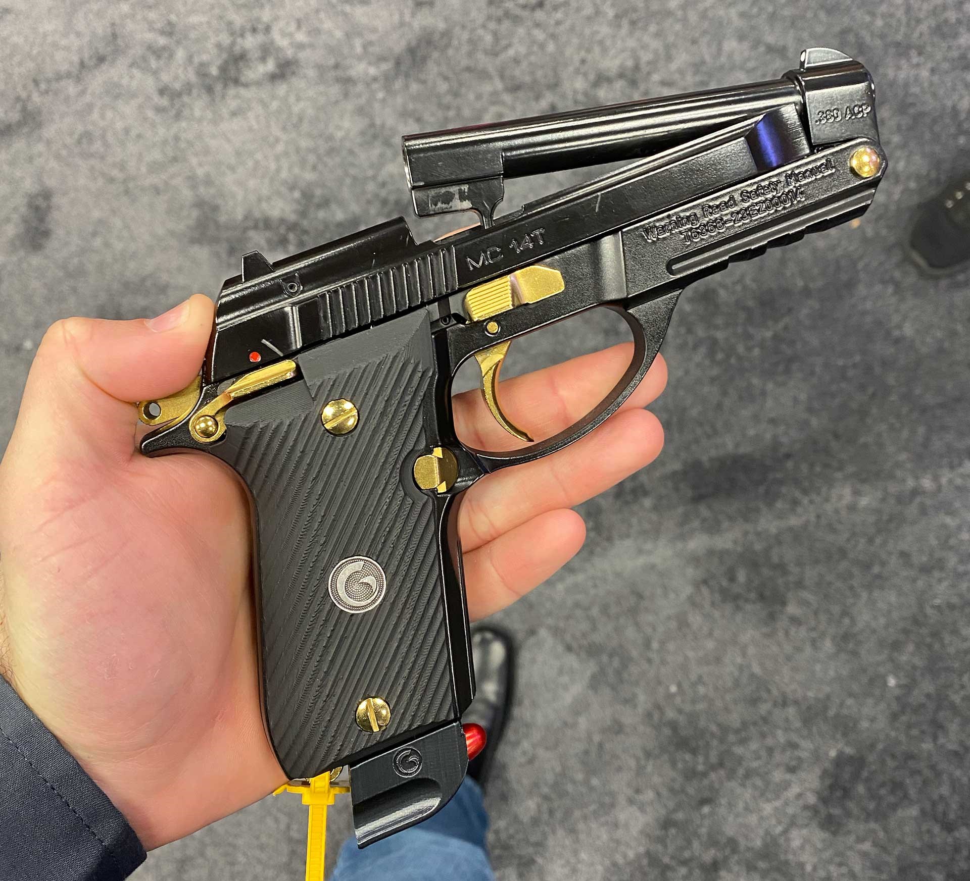 A black EAA MC 14T with gold controls held in a hand.