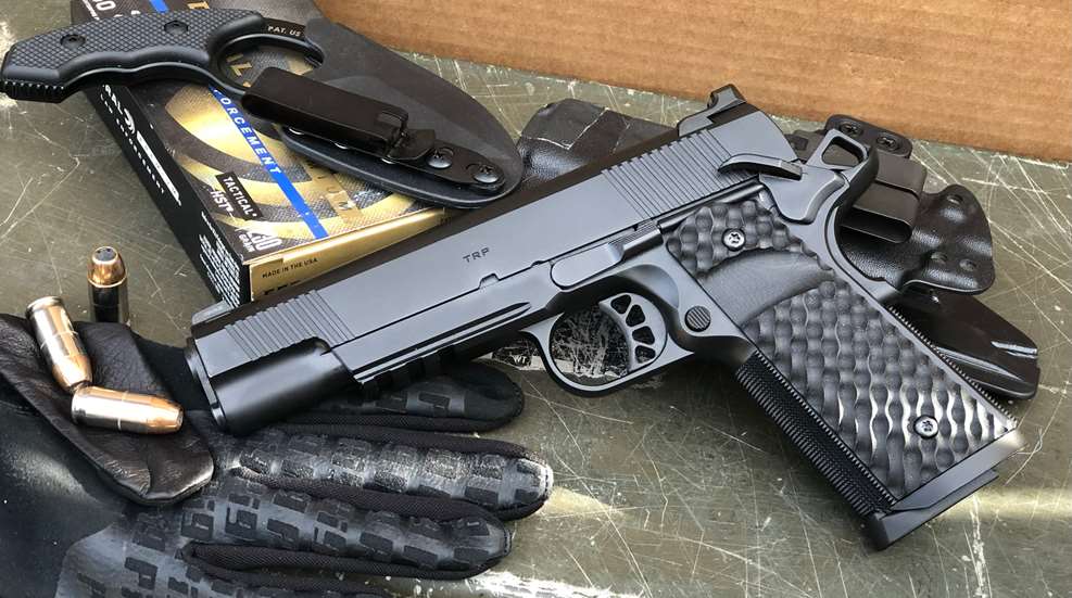 Black-colored Springfield Armory TRP 1911 left-side view shown with accessories gloves ammunition holster knife