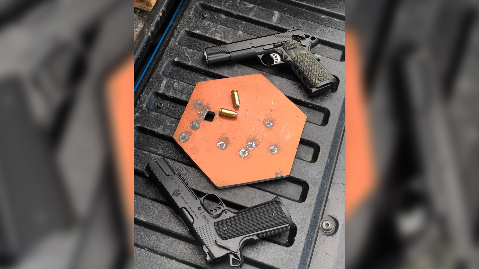 image overlay showing two springfield armory trp 1911 pistols with orange gong target with ammunition on truck tailgate