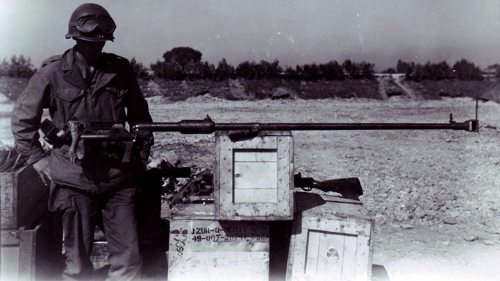 A U.S. soldier examines a bolt-action PTRD-41 anti-tank rifle chambered in  14.5x114 mm.