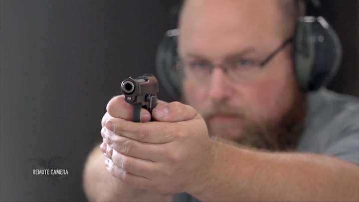 Man with protective shooting gear on a range with a Beretta pistol.