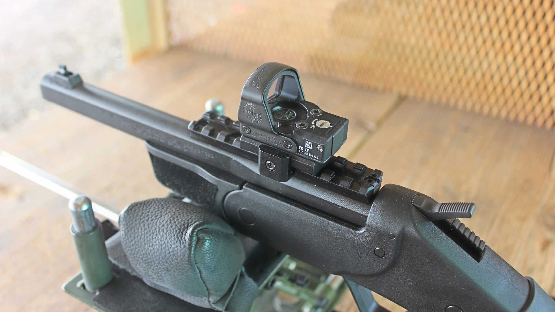 Rossi Brawler shown on bench with Leupold Delta Point Pro red-dot optic mounted on Picatinny rail top-down view wood table