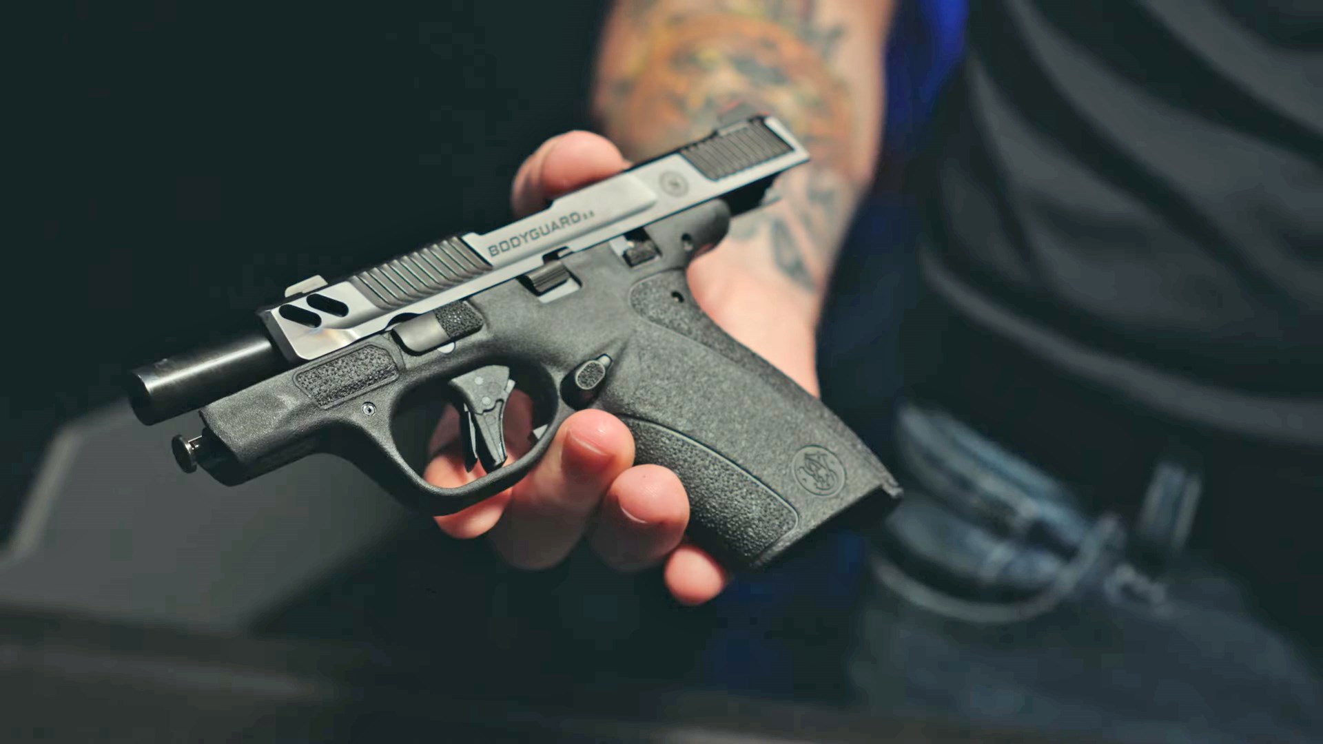 Man holding a Smith & Wesson Bodyguard 2.0 Carry Comp handgun with its slide locked back.