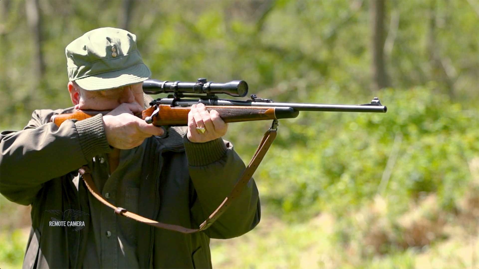A man aiming the Remington 700 BDL outdoors.