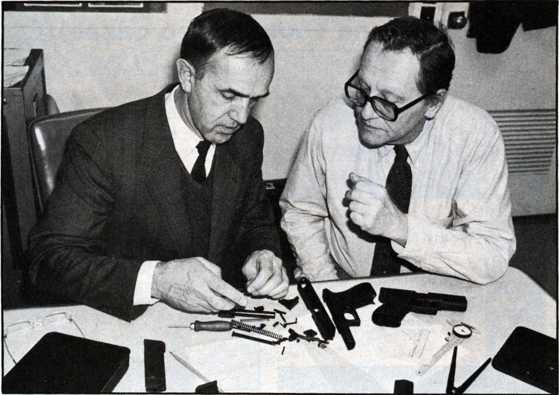 Two men sitting at a table, disassembling a Glock 17 pistol.