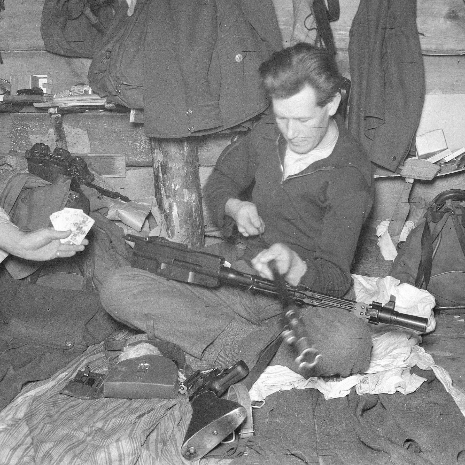 Armorer sitting with M/26 light machine gun in lap servicing parts