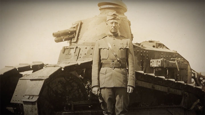 George S. Patton standing in front of a U.S. M1917 tank.