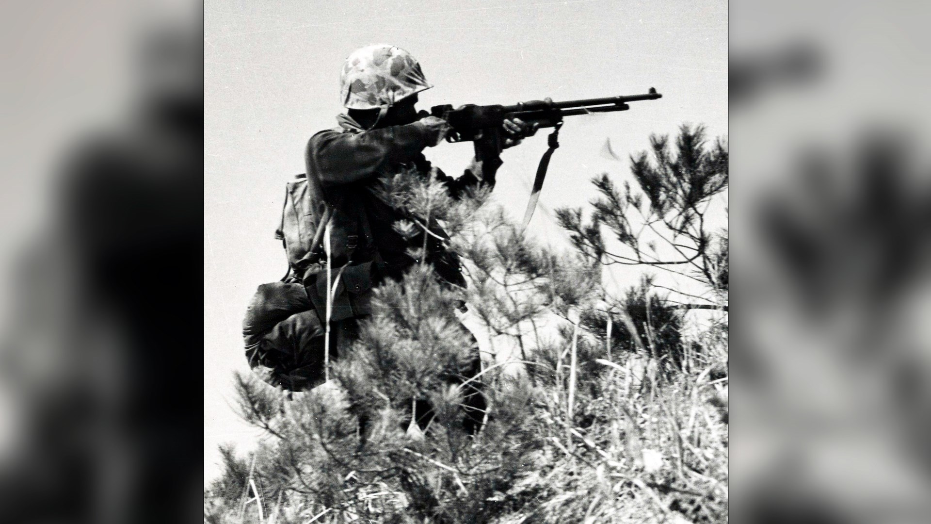 U.S. marine standing in bushes firing BAR