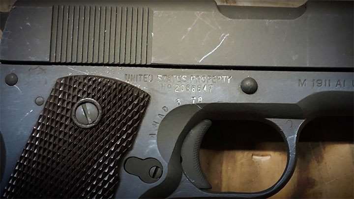 The rebuild markings visible on the frame of a rearsenaled M1911A1 pistol.