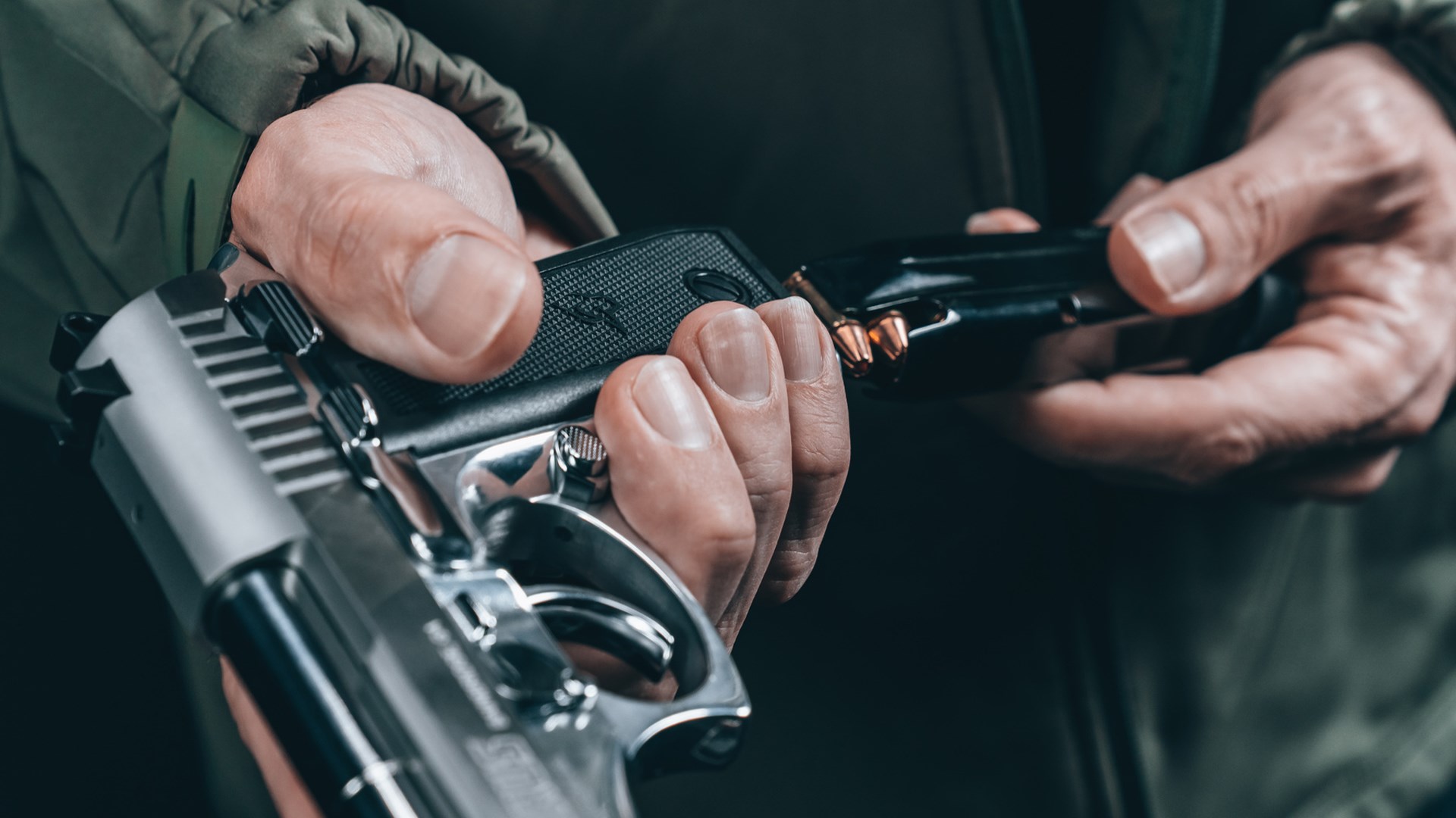 Man inserting a magazine into a stainless-steel Taurus 58 handgun.