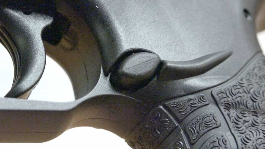 Close-up view of a black pistol&#x27;s magazine release button.