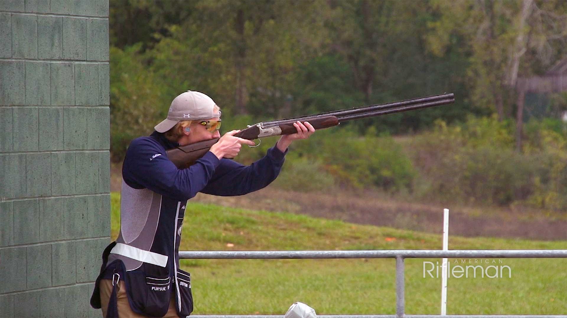 Man aiming an over-under shotgun on an outdoor shotgun range.