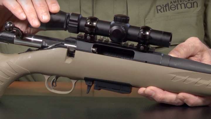 Rifle in hands of American Rifleman with one bolt at the rear and one hand on the optic.