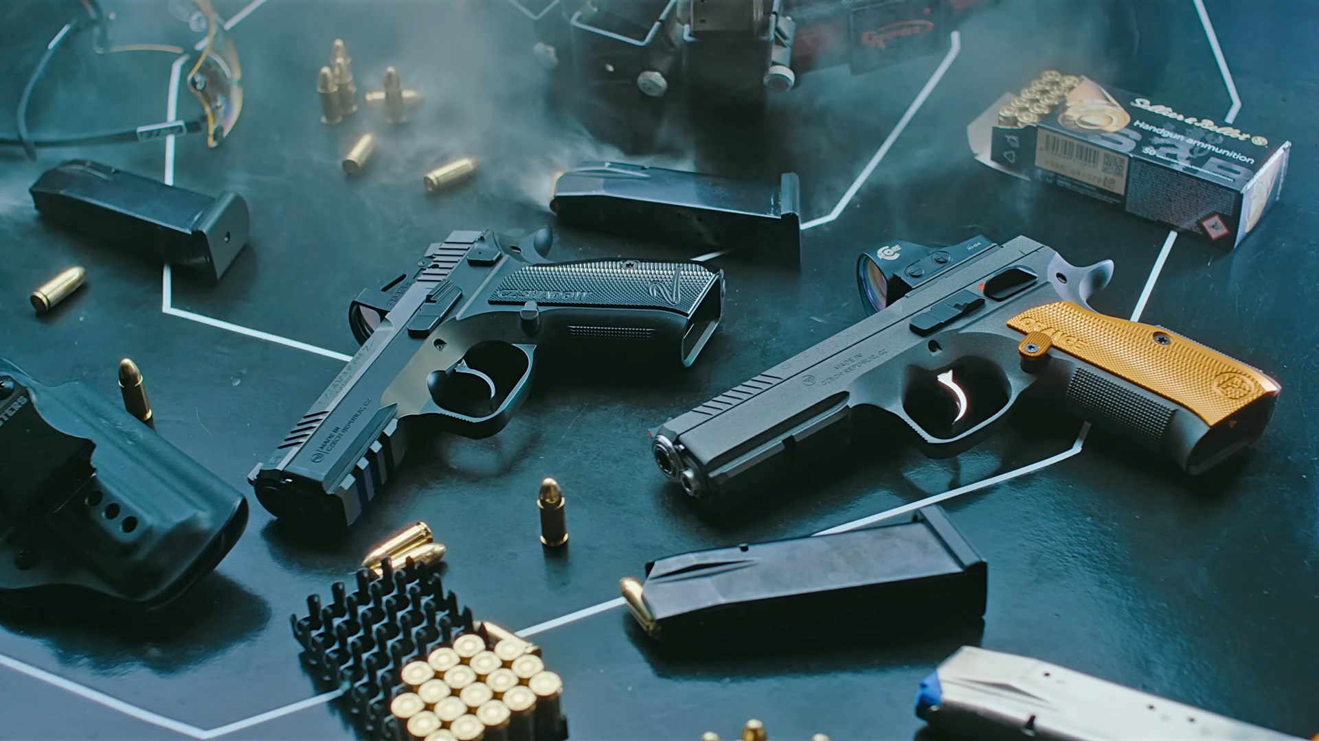 Two CZ Shadow 2 pistols laid down on a black target and surrounded by boxes of ammunition.