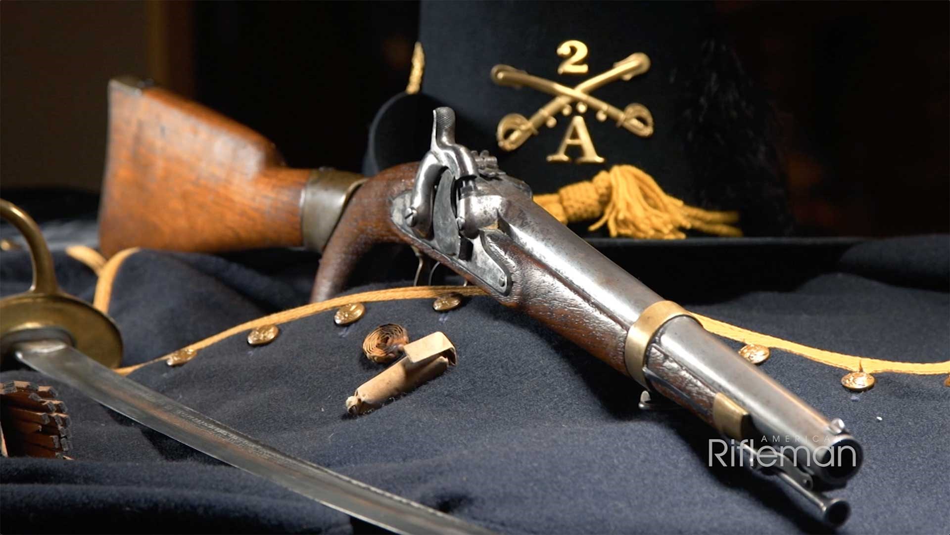 Model 1855 pistol carbine laying on a cavalryman's blue jacket next to a paper cartridge and a roll of Maynard tape primers.