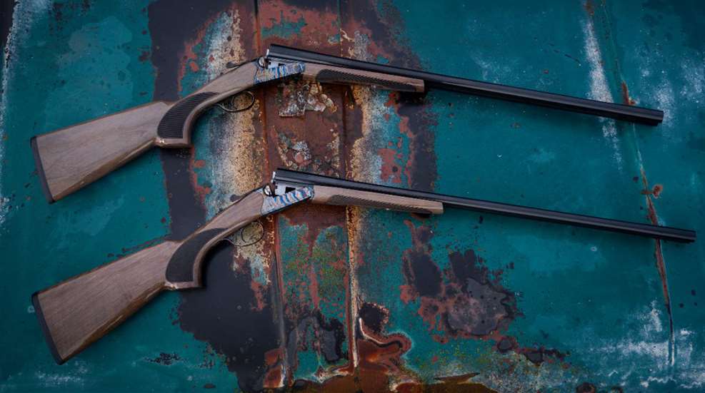 Two TriStar Arms Phoenix shotguns shown with their actions open on a faded metal surface.