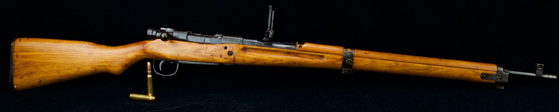 right-side view Arisaka bolt-action military surplus rifle japanese gun black background ammunition foreground bullets