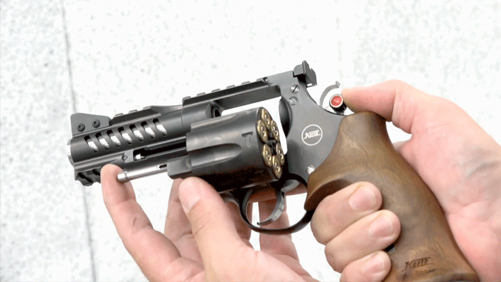 Revolver in hands with cylinder open and ready to unload ammunition.