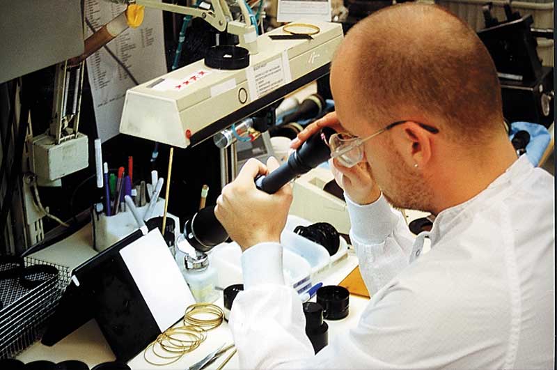 man looking through riflescope testing engineer lab white coat