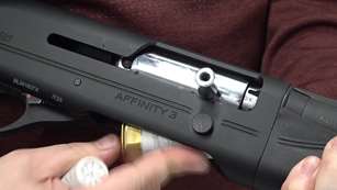 Close-up, right-side view Franchi Affinity 3 Sport Trap shotgun being loaded with white brass shotshell in hands