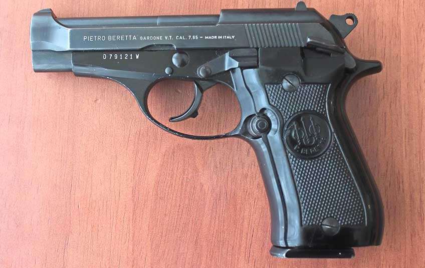 Left-side view of a black-colored Beretta Model 81 Cheetah placed on wooden table.