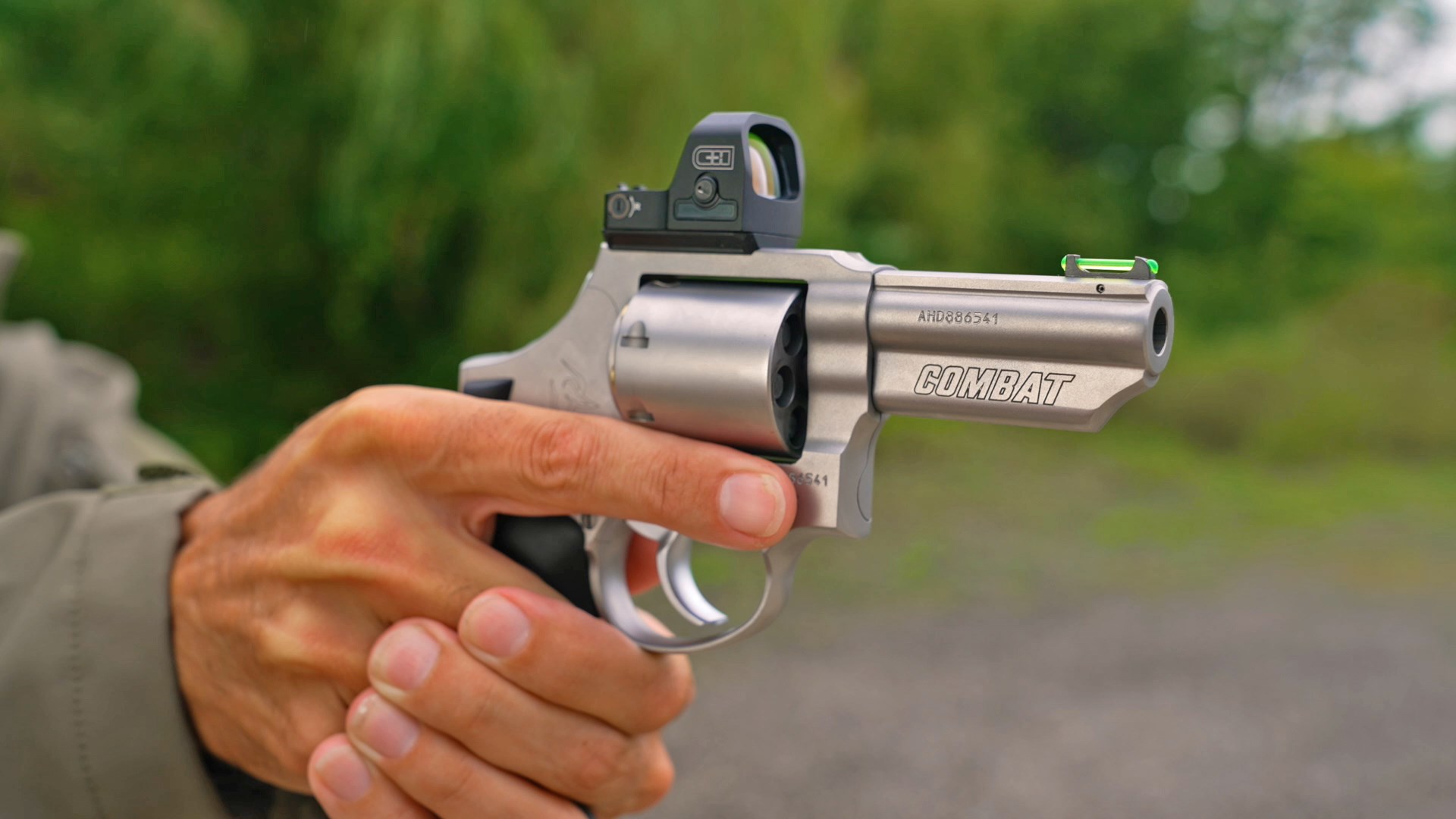 Hand aiming a Taurus 66 Combat revolver on an outdoor range.