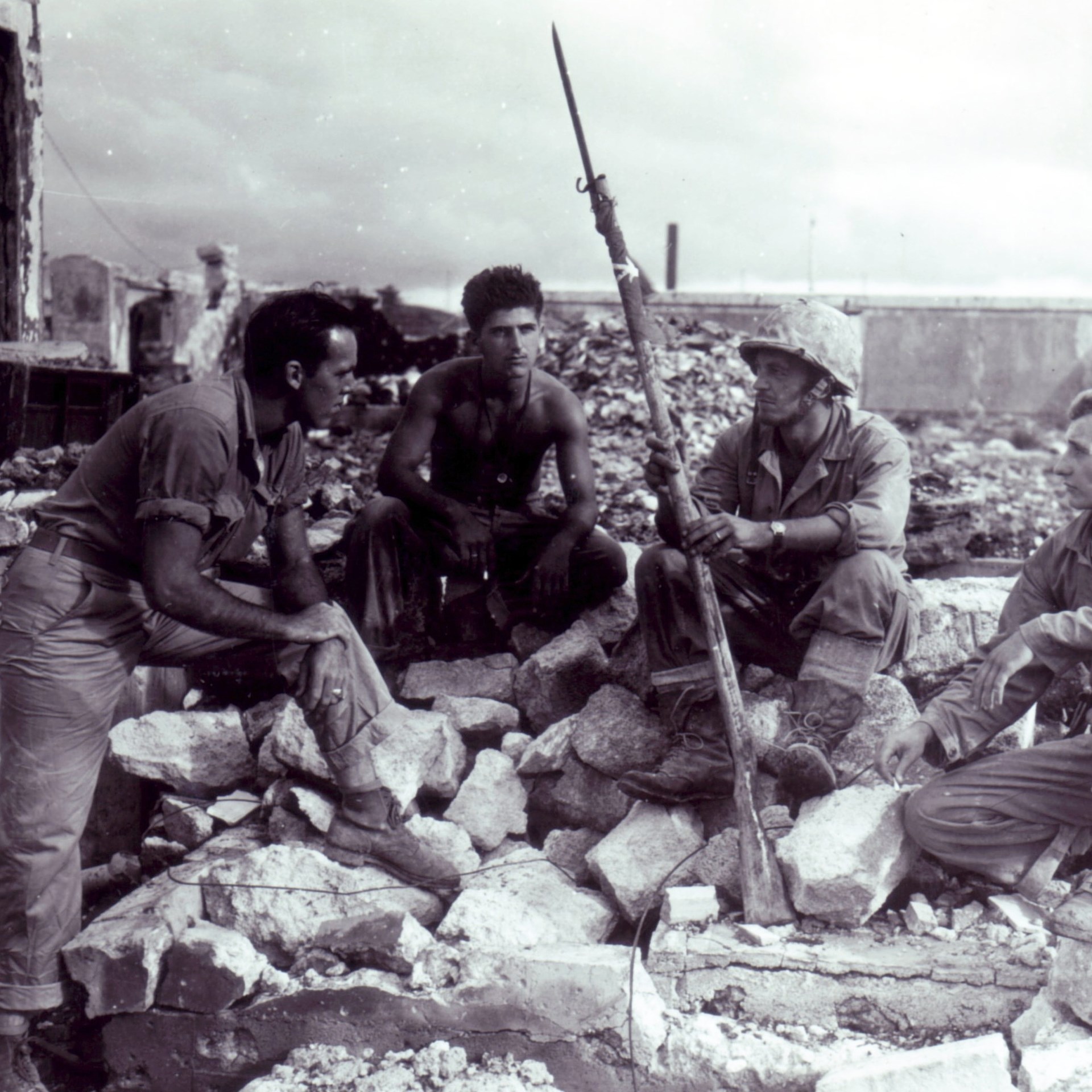 U.S. Marines circled around rubble and Banzai Stick in Japan 1945
