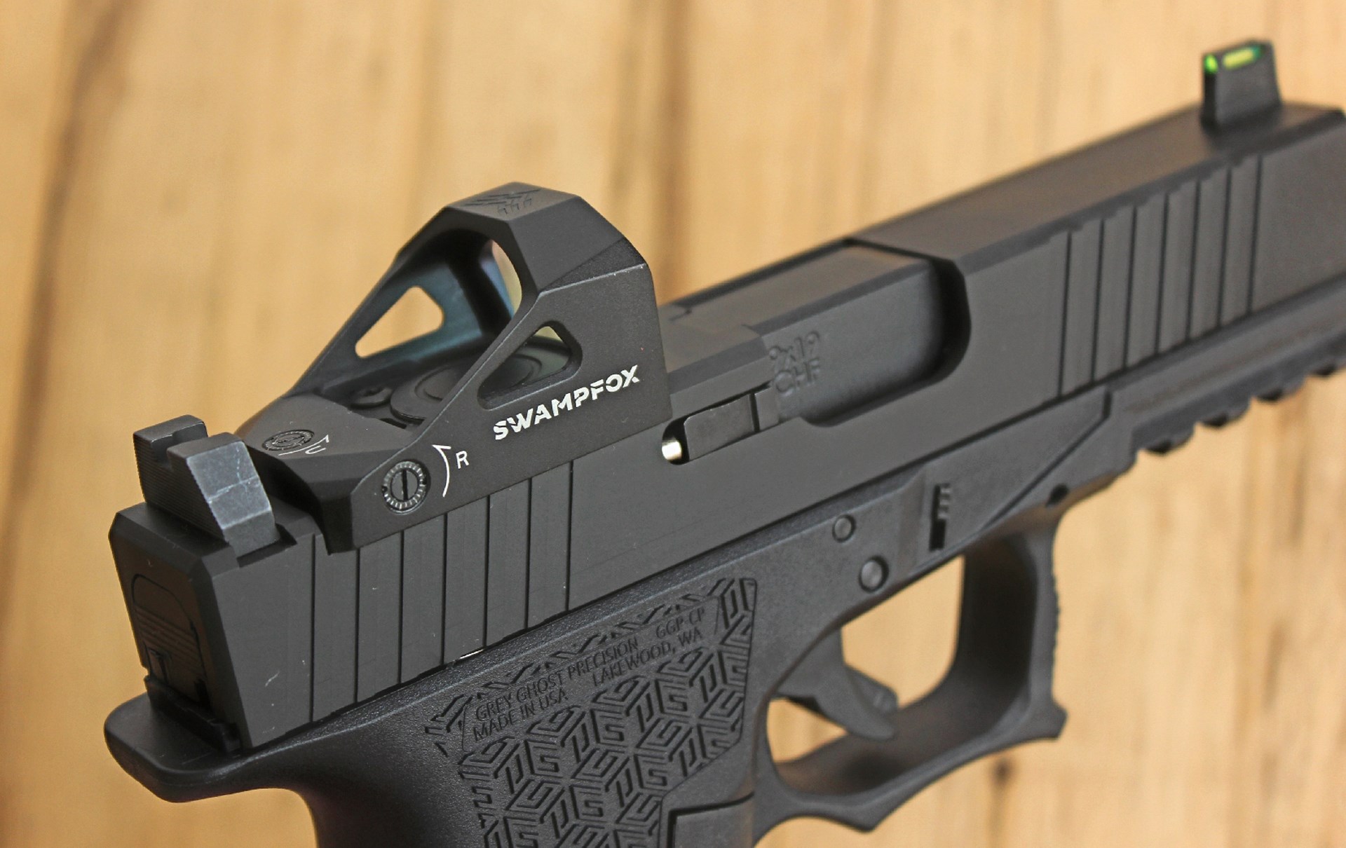 Swampfox red-dot optic shown on a black handgun wood background