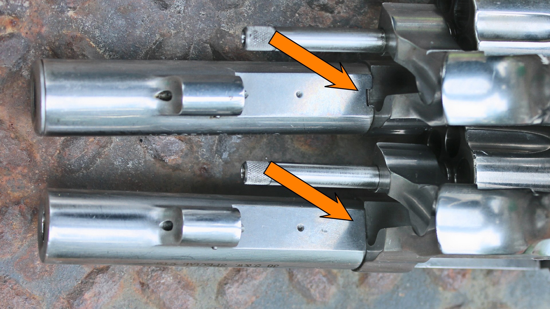 Smith & Wesson Model 64 648 side-by-side comparison stainless steel revolver barrel underside view shown with arrows illustrating mating surfaces of barrel shroud shown on rusted treadplate background
