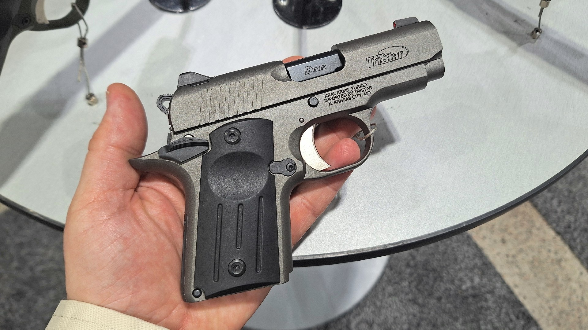 Tristar Arms Protege X 1911-pattern pocket pistol 9 mm held in hand at white table with other guns