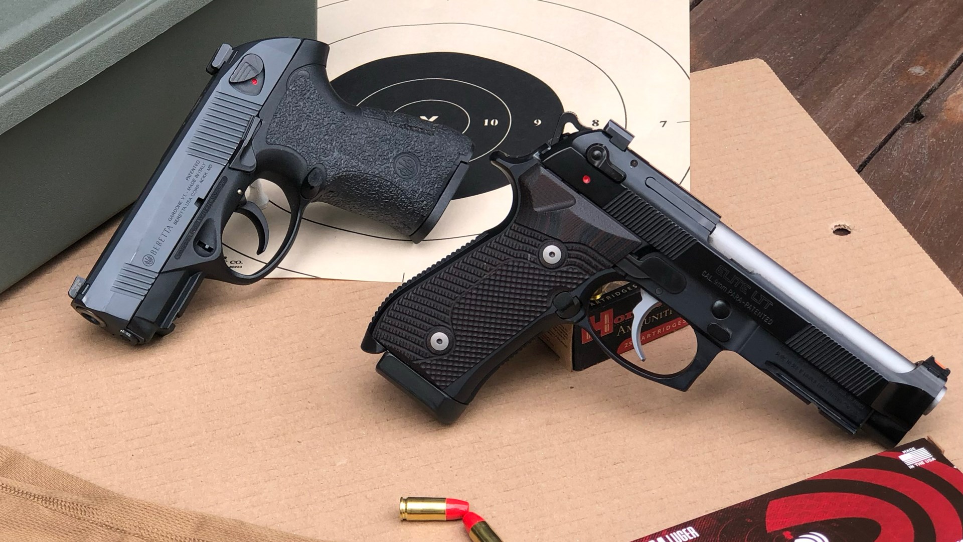 two pistols on cardboard target backer round black bullseye x rings ammunition box table wood background