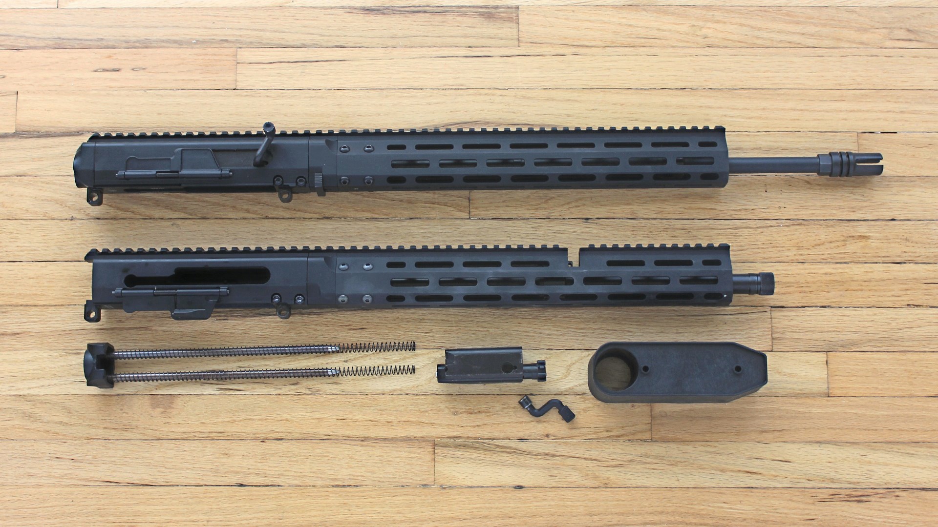 Upper receivers for AR-15-pattern guns shown with parts right-side view on wood flooring