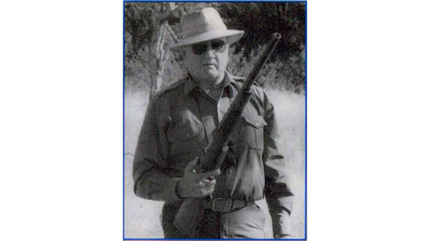 Col. Jeff Cooper shown with a large-bore rifle resting on his thigh while on safari.